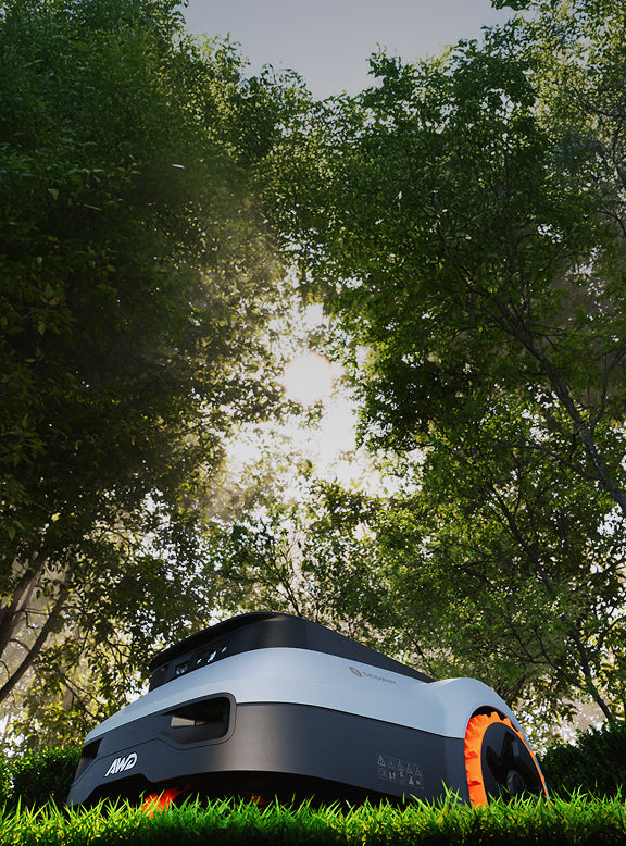 Segway Navimow AWD tondeuse robot sous des arbres au soleil.
